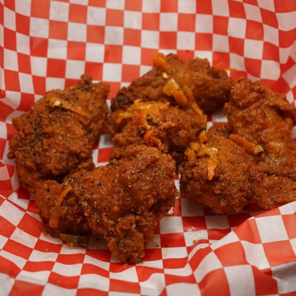 Crispy Wing It Los Angeles chicken wings with seasoning and orange zest in a red and white checkered basket.