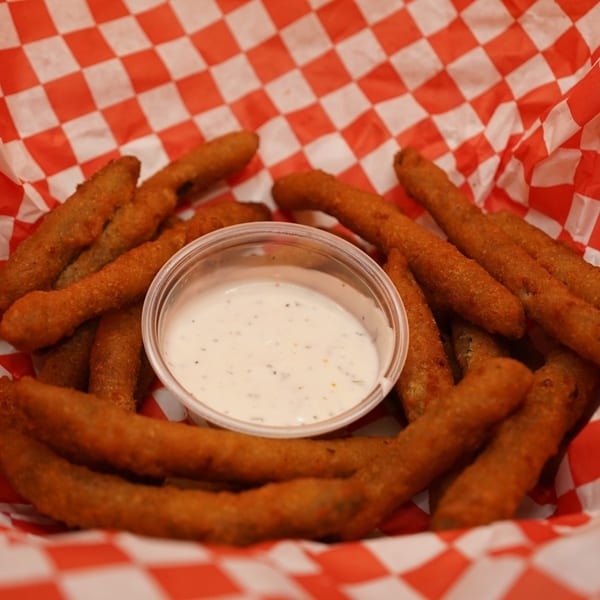Fried pickle spears with ranch dipping sauce in a red and white checkered basket at Wing It Los Angeles.