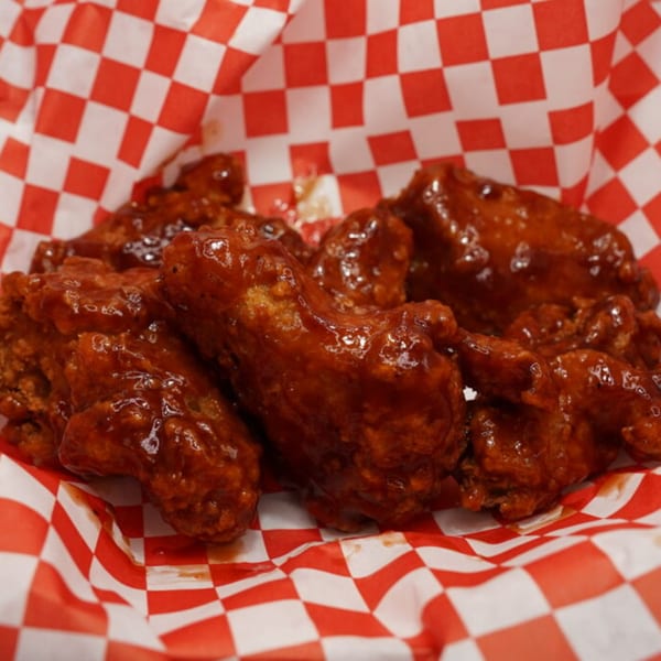 Wing It Los Angeles' saucy chicken wings in a red and white checkered paper-lined basket.